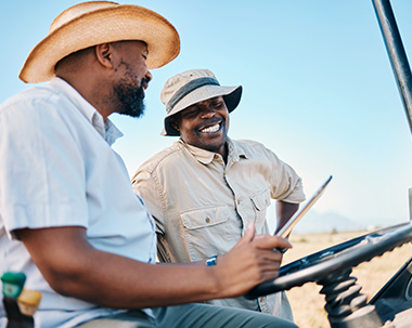 two safari tour guides smiling and looking at a tablet while sitting in a safari car